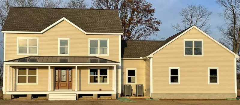 A yellow two-story house with a porch and an attached section.