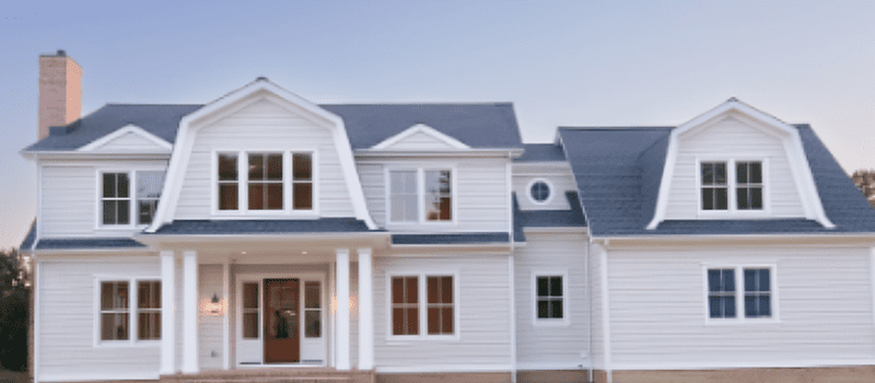 A modern white house with multiple windows and a dark roof.