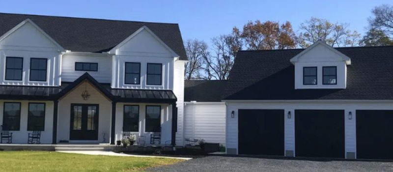 A modern two-story house with white siding and a dark roof.