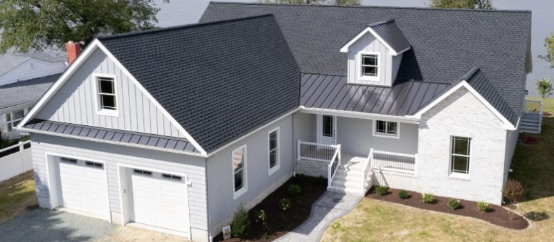 Modern house exterior with dark roof and white siding.
