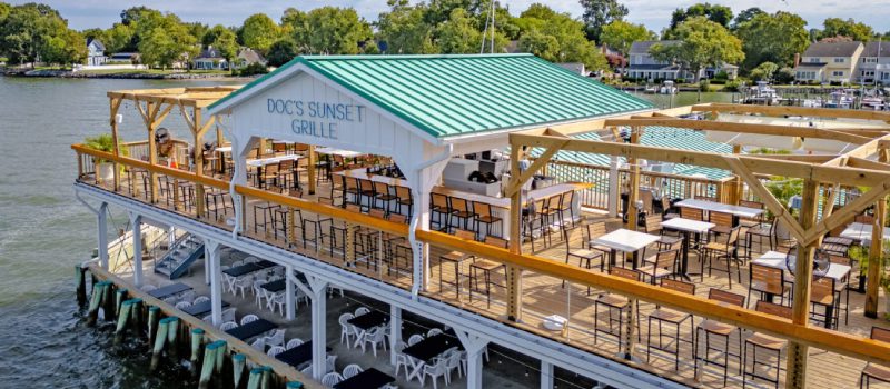 Outdoor dining area with wooden tables and green roof at Dock Sunset Grill.